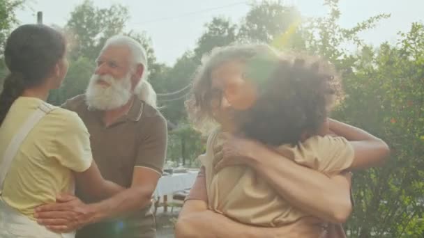 アフリカ系アメリカ人の男の子と少女は 裏庭でパーティーのために集まっている間 白人の祖父母にハグを贈ります — ストック動画