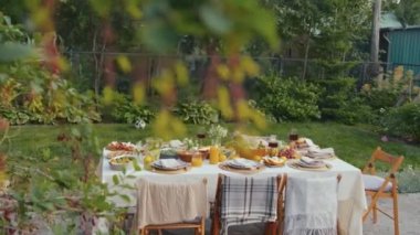 Yaz günü yemek, içecek, çiçek ve limonla süslenmiş yemek masasının geniş açılı görüntüsü yok.