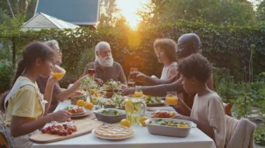 Modern Afro-Amerikan ve beyaz ailelerin aileleri yaz akşamları dışarıda yemek yiyorlar.