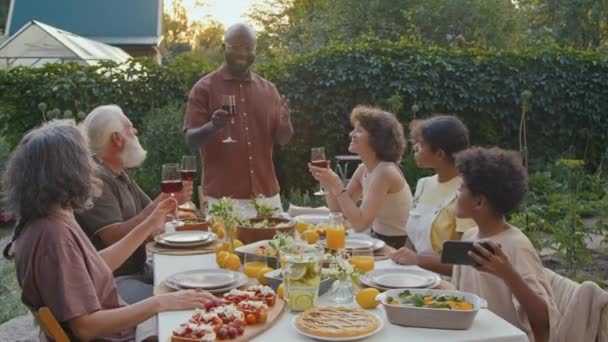 Многонациональная Семья Устраивает Праздничный Ужин Заднем Дворе Разговаривая Затем Машет — стоковое видео