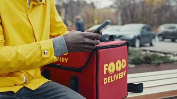 Yemek Dağıtım Elemanının Yakın Çekim Görüntüsü Elinde Çantasıyla Bankta Oturuyor — Stok video