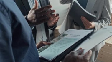 Çeşitli iş adamlarının yavaş çekimde toplanıp ofiste el hareketleriyle doküman ve raporları tartışırken.