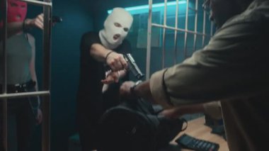 Siyahi bir tefeci, çantaya para koyarken, kar maskeli beyaz haydutlar tarafından silahla tehdit edilirken orta eğimli bir el resmi.