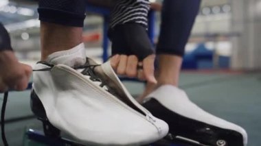 Erkek ellerinin kapalı spor salonundaki paten bağcıklarını sıkıca bağlarken çekilen tanınmayan el kamerası görüntülerini kapatın.