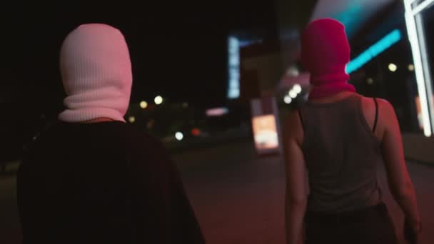 スローモールティルトハンドヘルドバックショット 明るいバラクーバーで2人の若い白人強盗が夜に銃とバッグで通りを歩いている — ストック動画