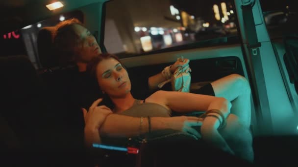 夜にアルコールで駐車された車でリラックスした若い白人カップルの中側のハンドヘルドショット — ストック動画