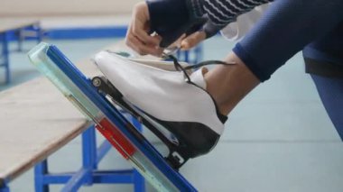 Tanımlanamayan alçak kısımları kapatın. Çift ırklı erkek ellerinin kapalı buz pateni sahasında paten kaymadan önce paten kılıflarıyla bağcıklarını sımsıkı bağladığı görüntüler.