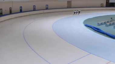 Buz pistinde koşan ve antrenman sırasında köşeyi dönen çok ırklı erkek sporcuların yüksek açılı geniş açılı çekim alanı.