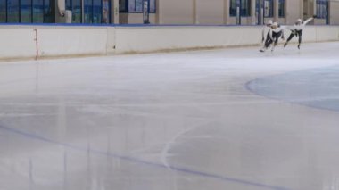 Antrenman sırasında çok ırklı erkek hız patencilerinin yavaş çekimleri köşeyi dönüyor. Buz pateni pistinde diğer sporcuları sollayan atlet.