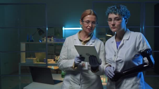 タブレットコンピュータで中年 義肢を持った若い女性2人のコカシア人女性科学者と 自信を持ってカメラを見つめ 化学実験室で一緒にポーズをとる中年の肖像画 — ストック動画