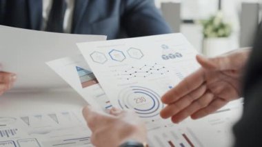 Ofisteki belgeleri kullanarak istatistiksel verilerden bahseden tanınmayan iki genç iş adamının yakın plan görüntüleri.