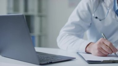 Tanımlanamayan bir erkek doktorun laptoptaki bilgilere bakıp hastane çalışma saatlerinde tıbbi geçmişine yazdığı yakın çekim.