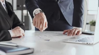 Ofiste oturan kadın iş ortağına proje belgesinde duran ve bilgileri açıklayan tanınmamış iş adamının orta bölüm fotoğrafı.