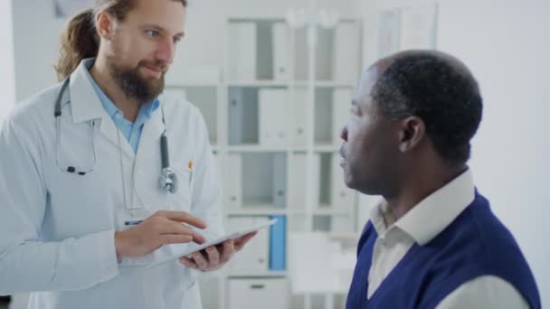 Medium Side Shot Caucasian Practitioner Tablet Asking Black Male Patient — Stock Video