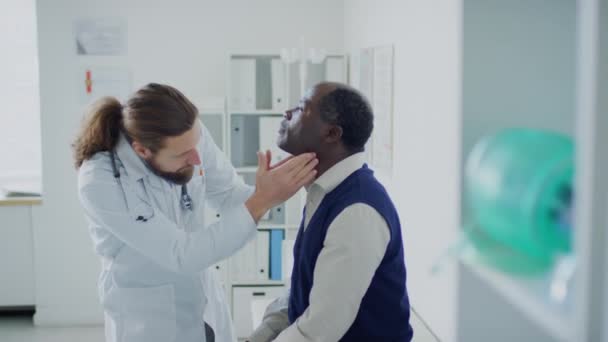 Średnie Ujęcie Boczne Kaukaskiego Lekarza Sprawdzającego Tarczycę Szyi Afroamerykańskiego Pacjenta — Wideo stockowe