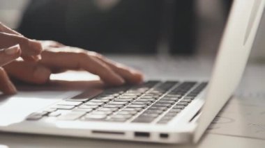 Ofiste güneşli bir günde klavye kullanarak bilgisayarına veri yazan kadınların yavaş çekimini kapat