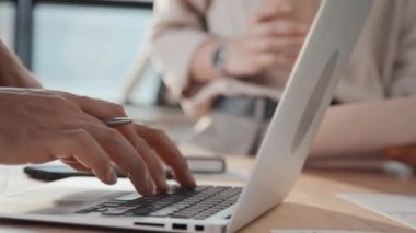Ofiste çalışırken tanınmayan erkek ofis çalışanlarının dizüstü bilgisayarda yazı yazarken, klavye ve dokunmatik kağıt kullanırken yakın plan çekimleri.