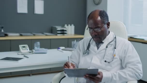 Portret Mediu Medicului Negru Sex Masculin Ochelari Stetoscop Stând Scriind — Videoclip de stoc