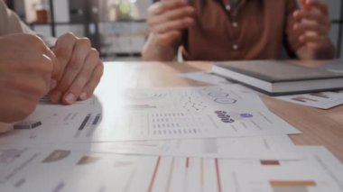 Ofisteki proje belgelerinde, günlük giysiler içinde iki tanınmayan iş ortağının grafiklere işaret etmesi ve istatistiksel verilerle pazarlık etmesi