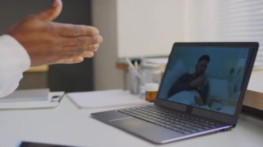 Hastanedeki dizüstü bilgisayarla hasta hasta ile çevrimiçi video görüşmesi yapan tanınmayan bir doktorun yakın çekim görüntüsü.