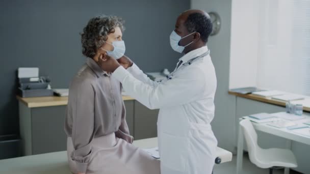 Средний Боковой Снимок Афроамериканца Маске Лица Щупающего Шею Белой Пациентки — стоковое видео