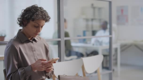 Средний Снимок Нетерпеливой Белой Женщины Сидящей Телефоном Больничном Коридоре Ожидающей — стоковое видео