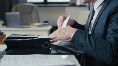 Tanımlanamayan bir iş adamının evrak ve dizüstü bilgisayarını çantasından çıkarıp ofiste çalışmaya başlaması.
