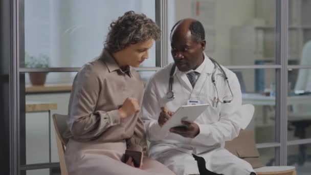 클리닉 복도에 코카서스 환자에게 진단을 스테로스코프와 태블릿 실무자의 — 비디오