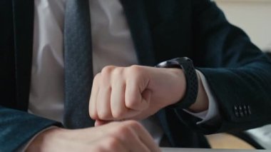 Ofiste çalışırken tanınmayan bir iş adamının yakın çekimde akıllı kol saatindeki mesajları kontrol ederken çekilmiş yakın çekimler.