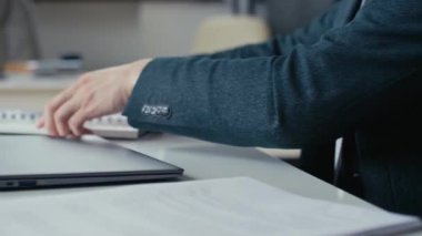 Ofiste çalışmaya başlamak için erkek eli kağıtları düzenlerken ve laptop açarken yakın plan çekimleri.