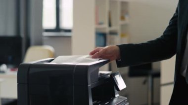 Tanımlanamayan bir ofis çalışanının belgesini ve kopyasını yazıcıdan alıp ofisten ayrılırken yan görüntüsü.