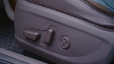 Tanımlanamayan bir sürücünün, mekanik koltuk ayarlarını kullanarak arabada otururken çekilmiş yakın çekim fotoğrafı.