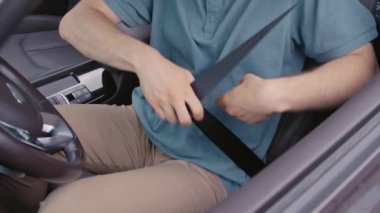 Araba kullanmadan önce tanınmayan sürücünün emniyet kemerini bağladığı orta büyüklükte kesilmiş bir fotoğraf.