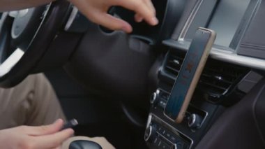 Tanımlanamayan sürücülerin yakın plan çekimleri. Araba kullanmadan önce telefonu şarj etmek için kabloyu takan eller.
