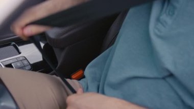 Tanımlanamayan sürücünün araba sürmeden önce emniyet kemerini taktığı yakın çekim.
