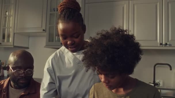 身穿医生制服的非洲裔美国女护士 丈夫和10岁的儿子一起站在厨房用面包 火腿和生菜沙拉做三明治的特写镜头 — 图库视频影像