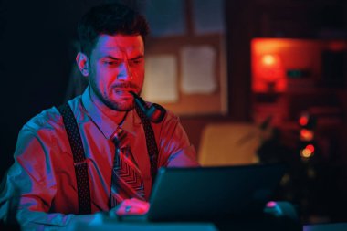 Genç ciddi işadamı daktilo ve pipo içerken iş yerinde oturup mesajlara bakarak bir şeyler düşünüyor.