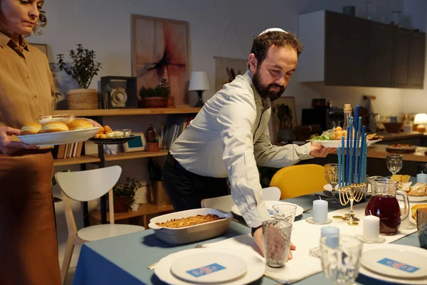 Бородатый Еврей Ермолке Помогает Жене Подавать Праздничный Стол Домашней Едой — стоковое фото