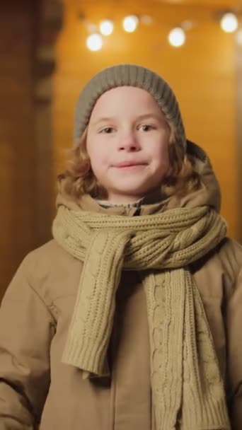 头戴冬衣 头戴圣诞彩灯 站在村舍旁边的儿童的垂直中肖像画 — 图库视频影像