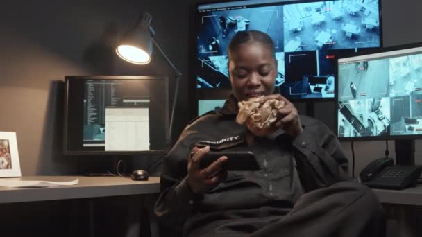 Μέτριο Πλάνο Του Νεαρού Απρόσεκτου Αφροαμερικανού Αξιωματικού Ασφαλείας Τρώει Σνακ — Αρχείο Βίντεο