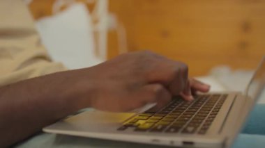 Dizüstü bilgisayarında yazı yazan tanınmayan siyahi bir adamın ellerinin seçici odak noktası.