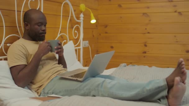 Mediana Toma Hombre Negro Sentado Cama Con Ropa Cómoda Bebiendo — Vídeo de stock