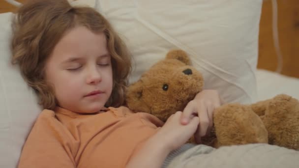 Średnie Zbliżenie Dziecka Falującymi Włosami Zasypiającego Łóżku Zabawką Niedźwiedzia Ramionach — Wideo stockowe
