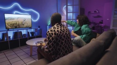 Gülümseyen çeşitli çiftin TV 'deki askerlerin neon ışıklı odasındaki kanepede oturduğu film zevkini çekerken yan görüntüsü.