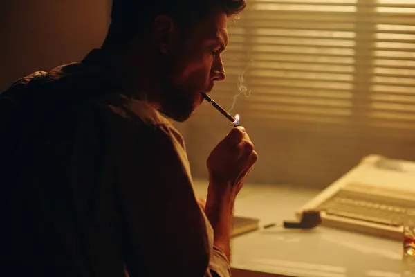年轻商人或作家坐在工作场所和窗前 头戴百叶窗抽烟的侧视图 — 图库照片
