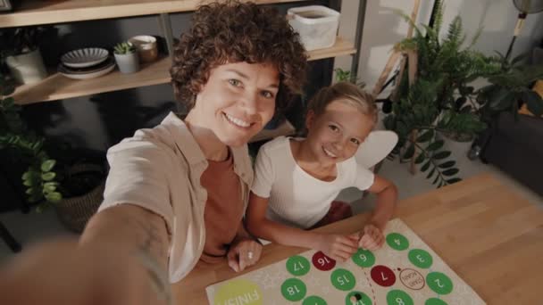 在厨房玩棋盘游戏的时候 一个快乐的女人拿着相机和她十几岁的女儿在一起自拍 这种高角速度的动作很慢 — 图库视频影像