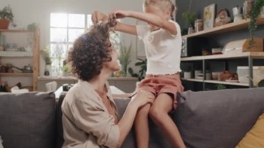 Modern anne ve kızın evde birbirlerini gıdıklayarak eğlendikleri yavaş çekim.