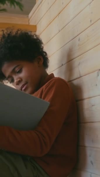 Вертикальный Снимок Афроамериканского Мальчика Сидящего Деревянной Лестнице Современном Коттедже Читающего — стоковое видео