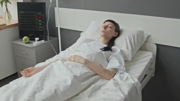 モニターの隣に横たわるIvの医療ポートを持つ睡眠カフカシア人女性の中型ショット — ストック動画