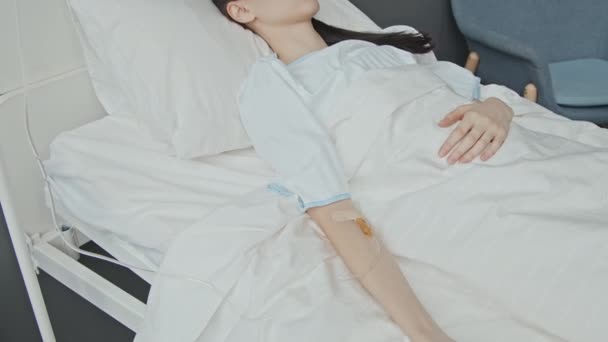 病院のベッドに横たわる無意識の白人女性の高角度は 彼女の腕の静脈内線を通って液体を得る — ストック動画